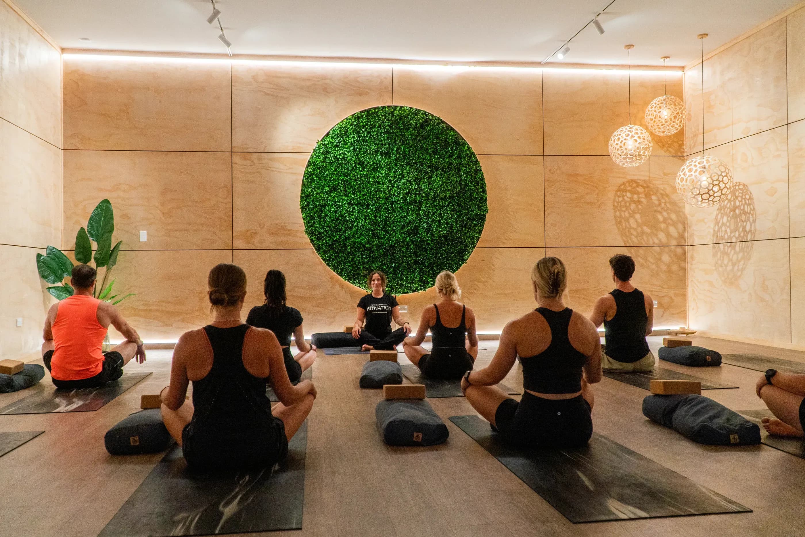 A yoga class seated on their mats facing the instructor at Fit Nation Mount Maunganui